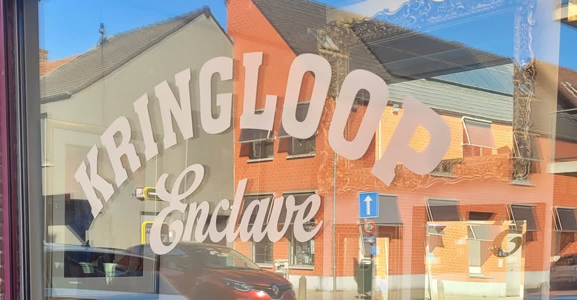 Etalage van Kringloop Enclave: KRINGLOOP in een boog, Enclave in schrift op het raam.